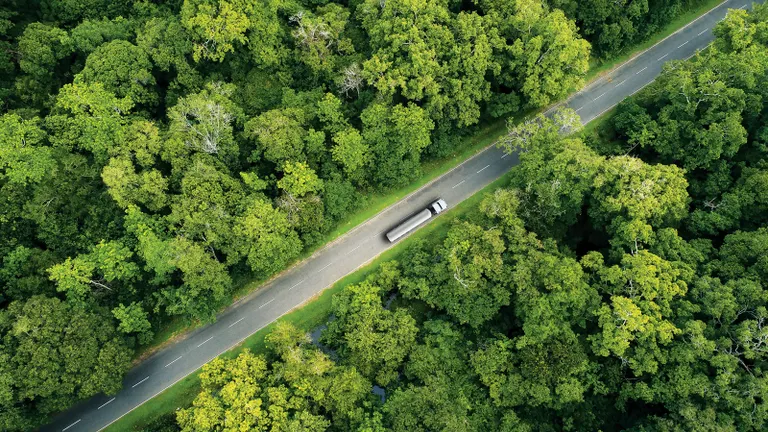 Tartályautó madártávlatból ahogy egy szép erdei úton halad