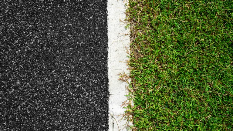 Aszfaltút széle felülnézetből, amelyet fű szegélyez